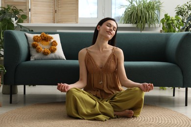 Photo of Harmony. Smiling woman meditating on floor at home
