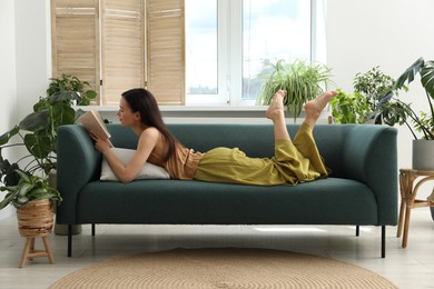 Photo of Harmony. Beautiful woman reading book on sofa at home