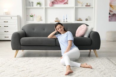 Photo of Harmony. Smiling woman relaxing while leaning on sofa at home