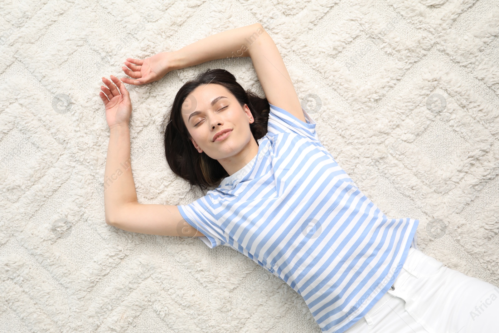 Harmony. Smiling woman lying on light carpet, top view Photo of Harmony. Smiling woman lying on light carpet, top view