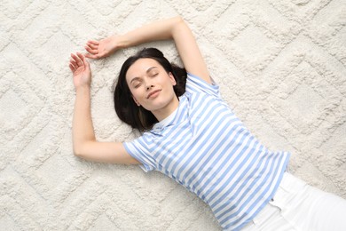 Photo of Harmony. Smiling woman lying on light carpet, top view