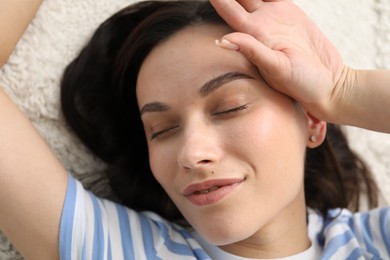Photo of Harmony. Smiling woman lying on light carpet, closeup
