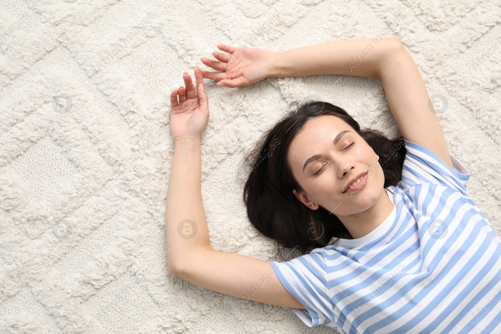 Harmony. Smiling woman lying on light carpet, top view Photo of Harmony. Smiling woman lying on light carpet, top view