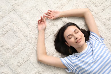 Photo of Harmony. Smiling woman lying on light carpet, top view