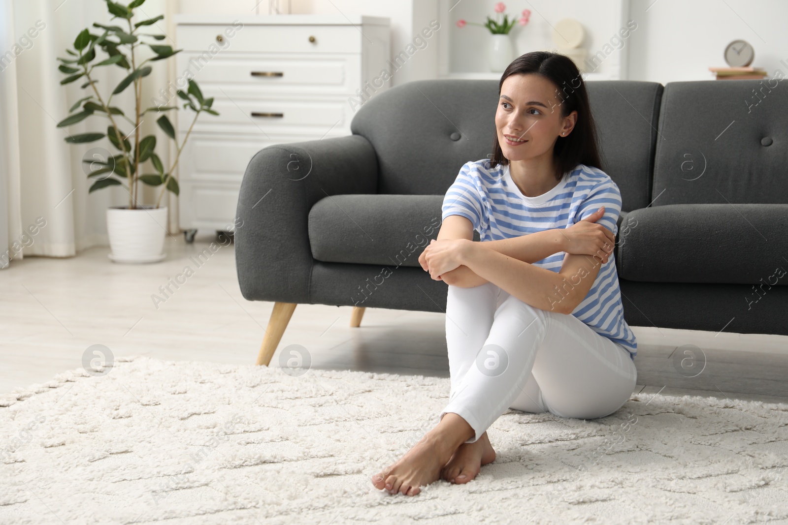 Photo of Harmony. Smiling woman sitting on floor at home