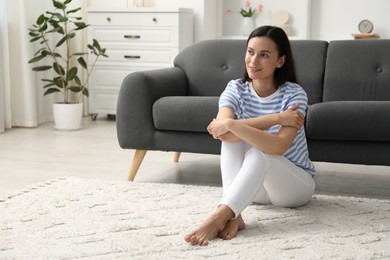 Photo of Harmony. Smiling woman sitting on floor at home