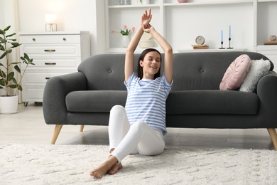 Photo of Harmony. Smiling woman stretching on floor at home