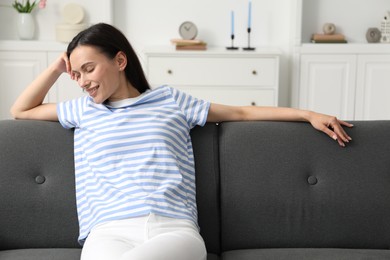 Photo of Harmony. Smiling woman sitting on sofa at home