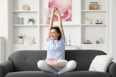 Photo of Harmony. Smiling woman stretching on sofa at home
