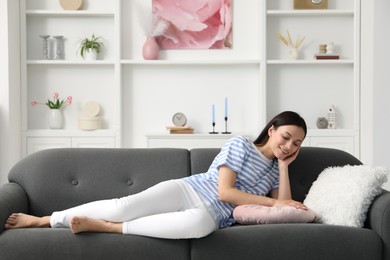 Photo of Harmony. Smiling woman lying on sofa at home