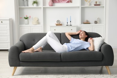 Photo of Harmony. Smiling woman lying on sofa at home
