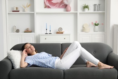 Photo of Harmony. Smiling woman lying on sofa at home