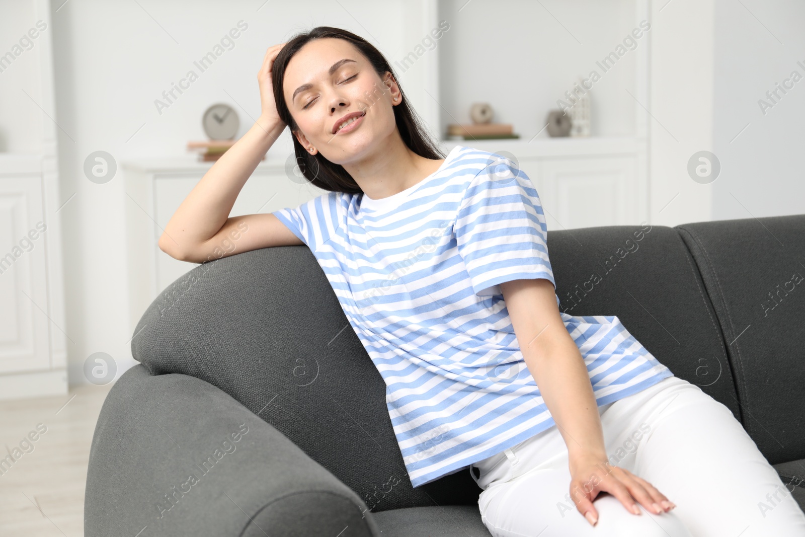 Photo of Harmony. Smiling woman sitting on sofa at home