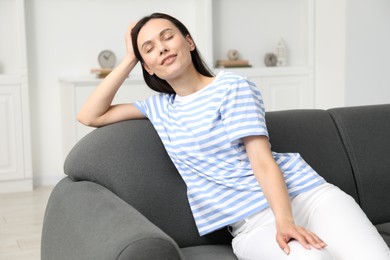Photo of Harmony. Smiling woman sitting on sofa at home