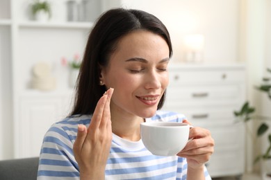 Photo of Harmony. Smiling woman with cup of hot drink relaxing at home