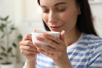 Photo of Harmony. Woman with cup of hot drink relaxing at home
