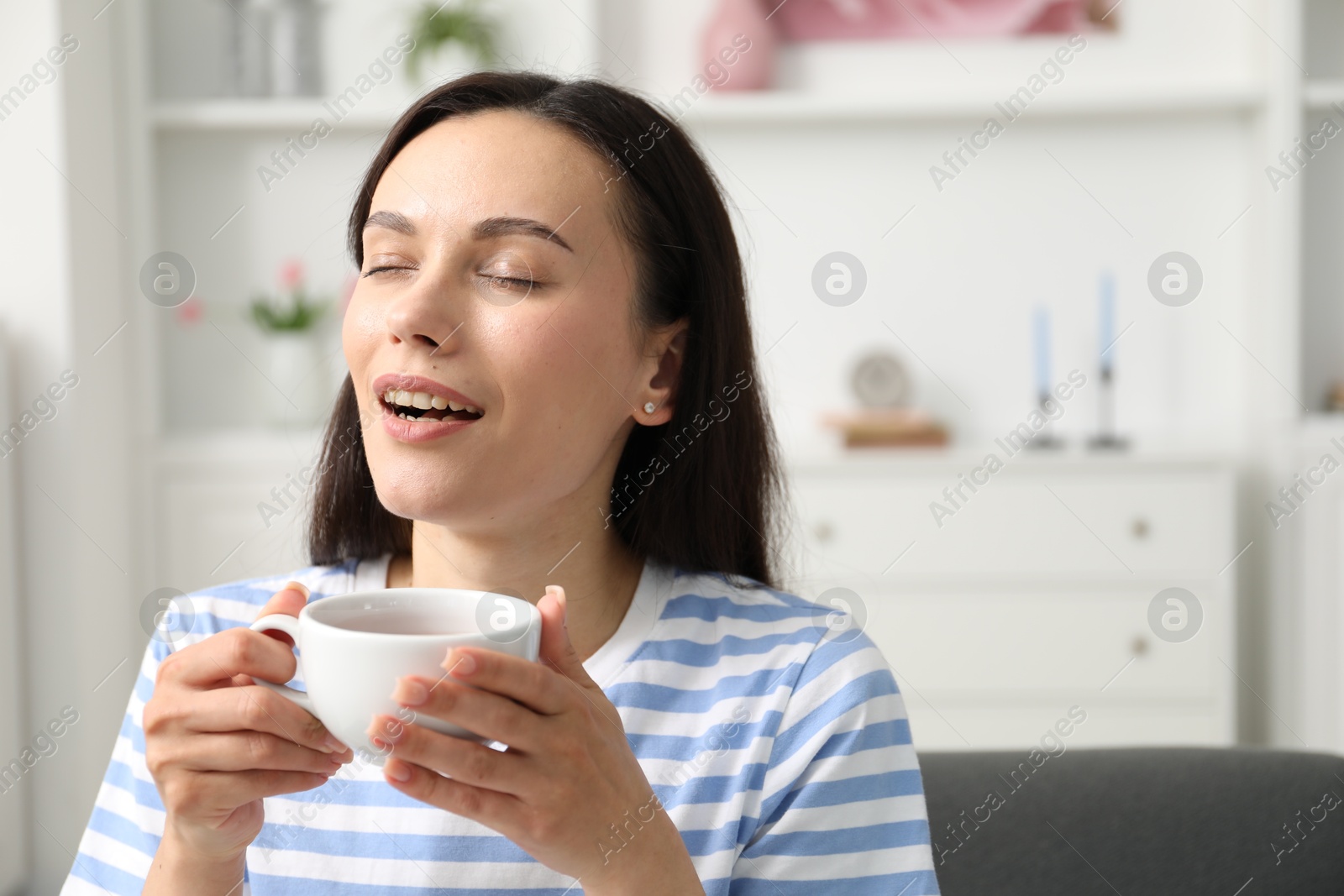 Harmony. Happy woman with cup of hot drink relaxing at home, space for text Photo of Harmony. Happy woman with cup of hot drink relaxing at home, space for text