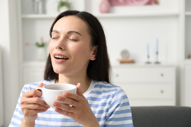 Photo of Harmony. Happy woman with cup of hot drink relaxing at home, space for text