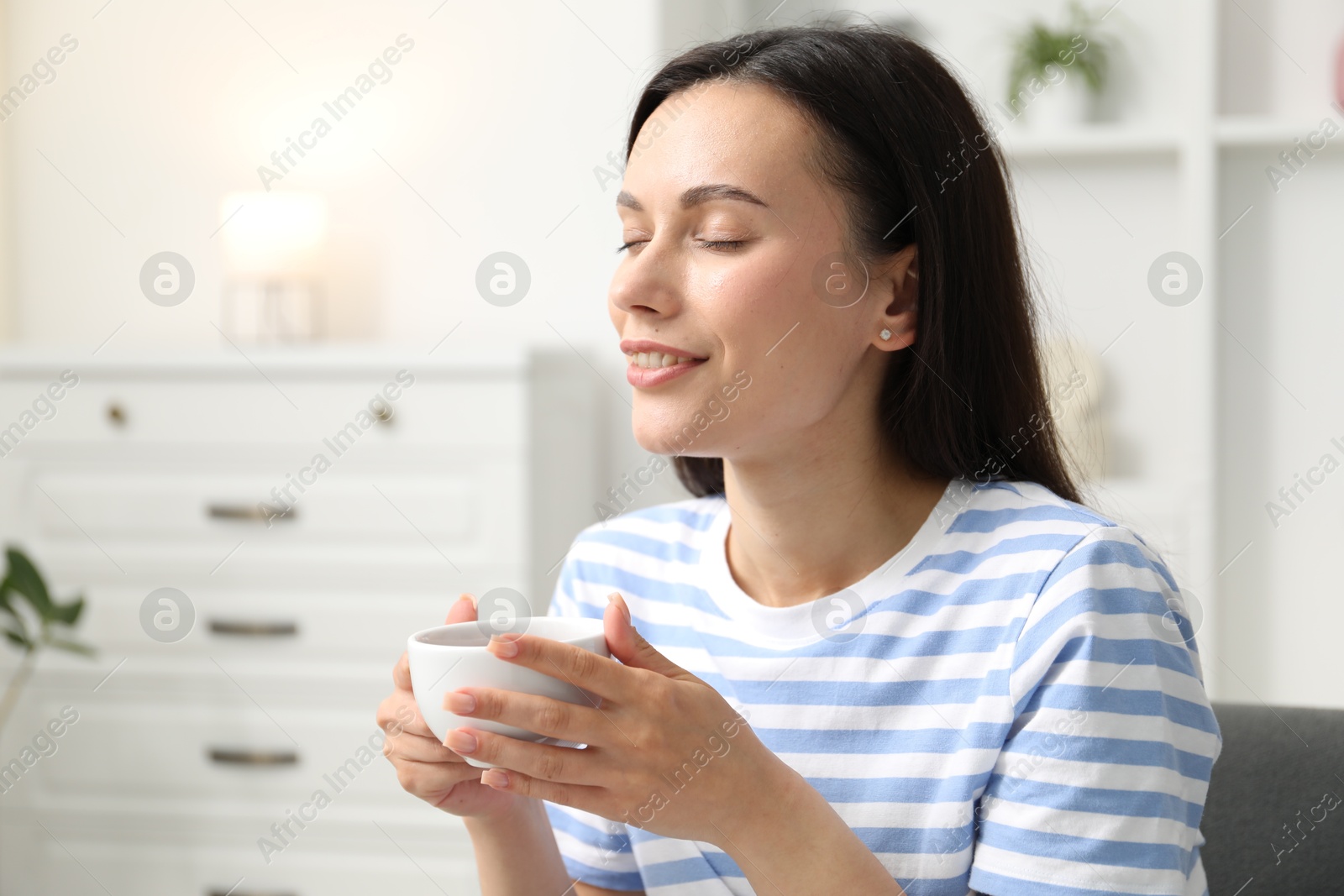 Harmony. Smiling woman with cup of hot drink relaxing at home Photo of Harmony. Smiling woman with cup of hot drink relaxing at home