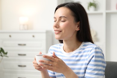Photo of Harmony. Smiling woman with cup of hot drink relaxing at home