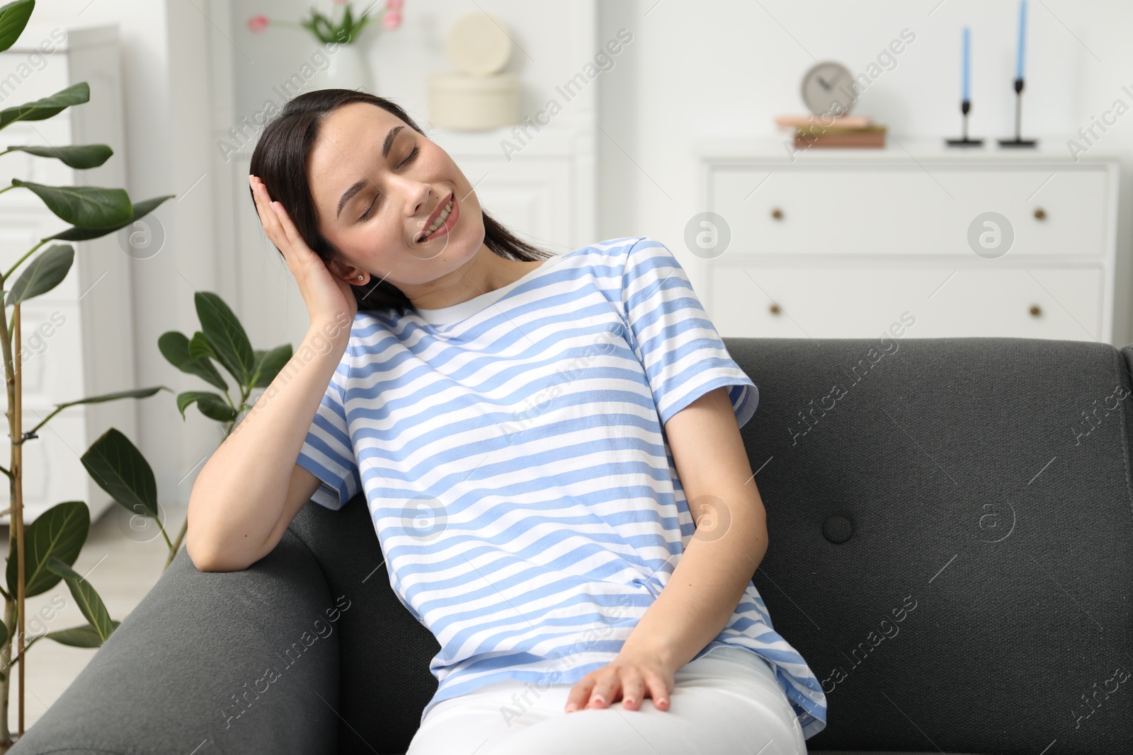 Photo of Harmony. Smiling woman sitting on sofa at home, space for text