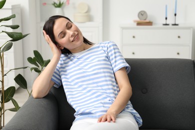 Photo of Harmony. Smiling woman sitting on sofa at home, space for text