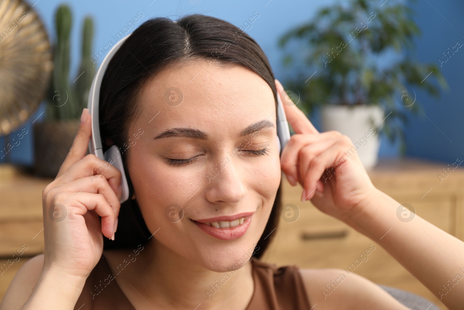 Harmony. Smiling woman in headphones enjoying music at home, closeup Photo of Harmony. Smiling woman in headphones enjoying music at home, closeup