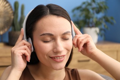 Photo of Harmony. Smiling woman in headphones enjoying music at home, closeup