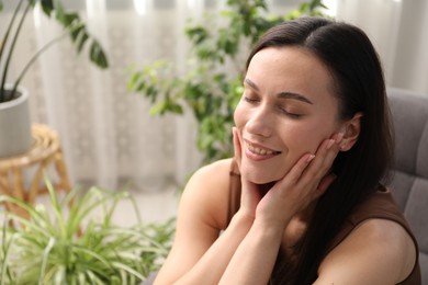 Photo of Harmony. Smiling woman relaxing on armchair at home. Space for text