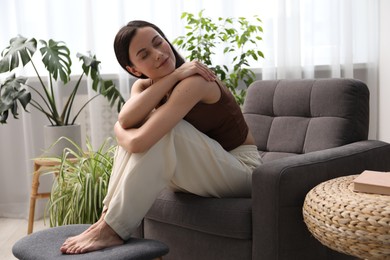 Photo of Harmony. Beautiful woman relaxing on armchair at home