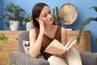 Photo of Harmony. Beautiful woman reading book on armchair at home