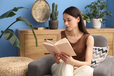 Photo of Harmony. Beautiful woman reading book on armchair at home