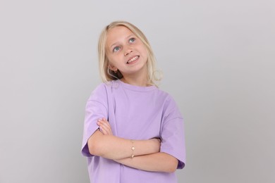 Photo of Portrait of happy girl on light grey background in photo studio
