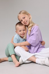 Photo of Little girl with her brother on light grey background in photo studio