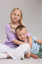 Photo of Little girl with her brother on light grey background in photo studio