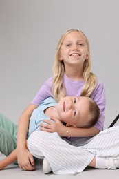 Photo of Little girl with her brother on light grey background in photo studio