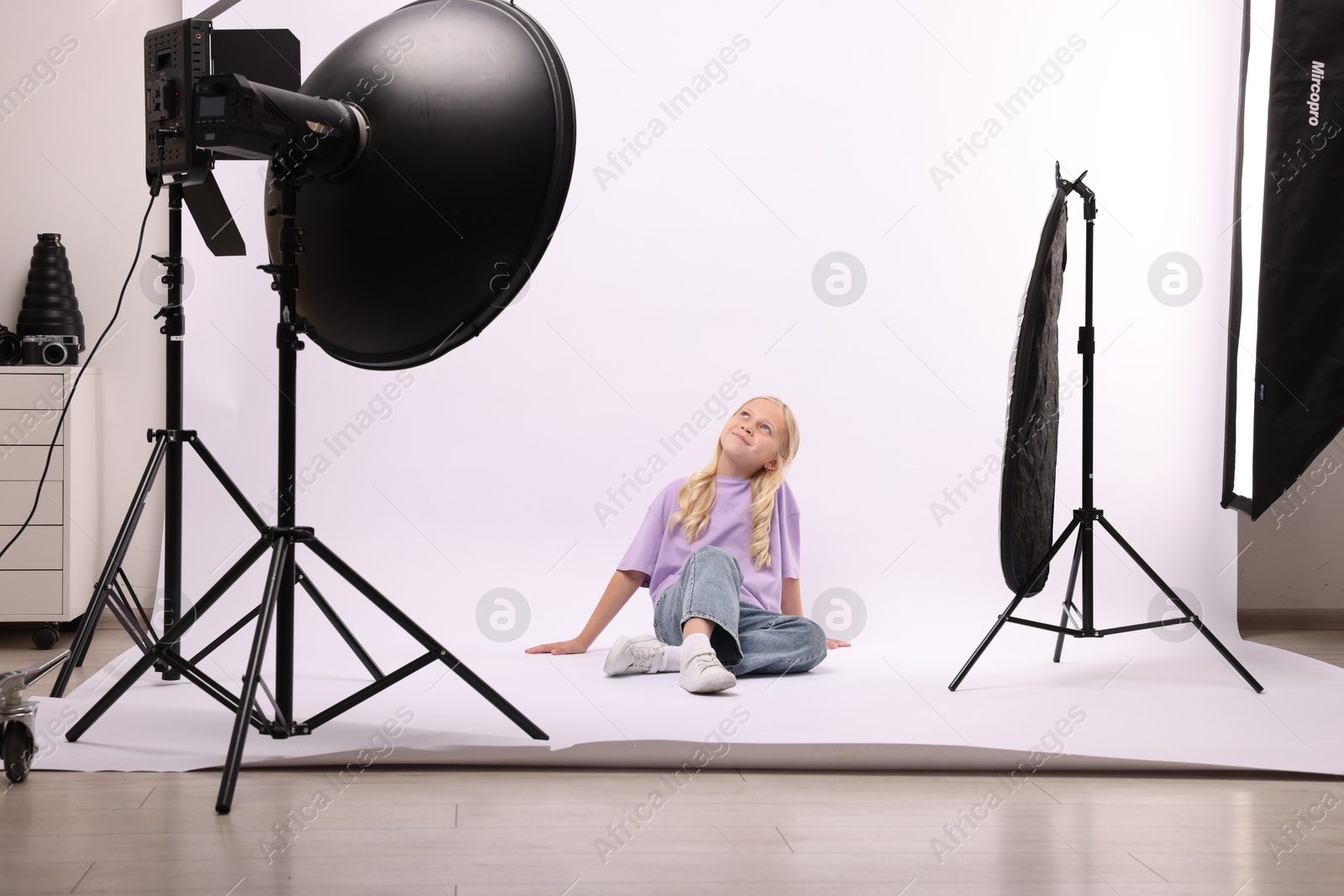 Little girl on white background in photo studio with professional equipment Photo of Little girl on white background in photo studio with professional equipment