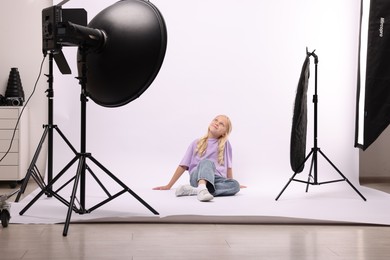 Photo of Little girl on white background in photo studio with professional equipment