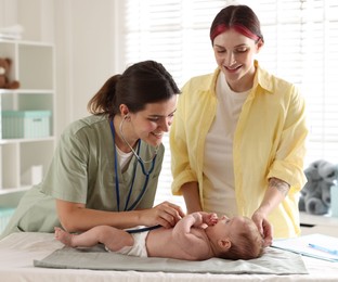 Photo of Mother and her cute little child having appointment with pediatrician in hospital. Doctor examining baby with stethoscope