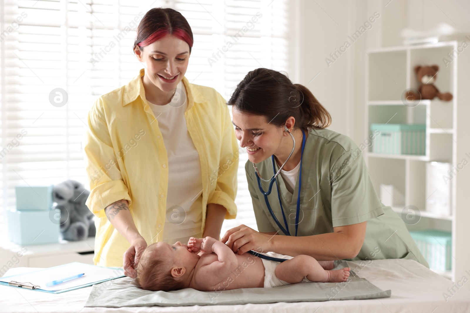 Photo of Mother and her cute little child having appointment with pediatrician in hospital. Doctor examining baby with stethoscope