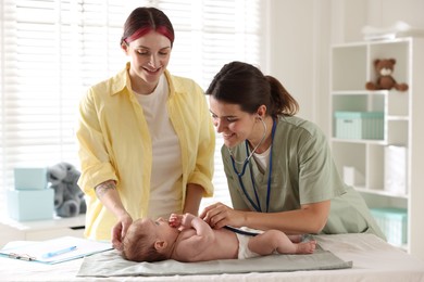 Photo of Mother and her cute little child having appointment with pediatrician in hospital. Doctor examining baby with stethoscope