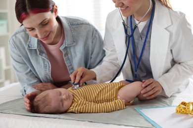 Photo of Mother and her cute little child having appointment with pediatrician in hospital. Doctor examining baby with stethoscope, closeup