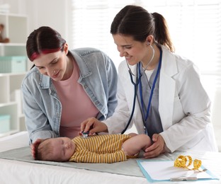 Photo of Mother and her cute little child having appointment with pediatrician in hospital. Doctor examining baby with stethoscope