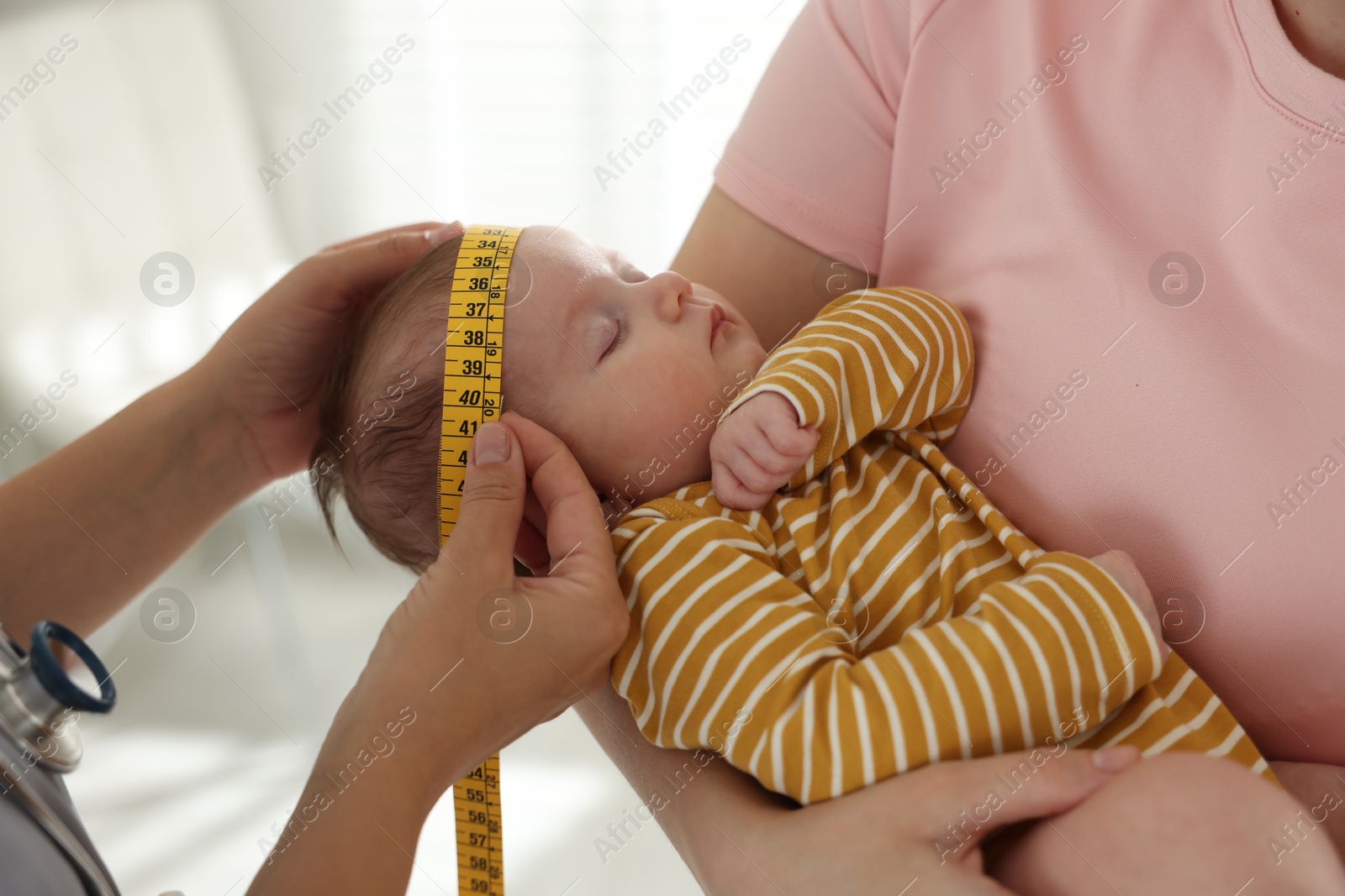 Mother and her cute little child having appointment with pediatrician in hospital. Doctor measuring baby's head, closeup Photo of Mother and her cute little child having appointment with pediatrician in hospital. Doctor measuring baby's head, closeup