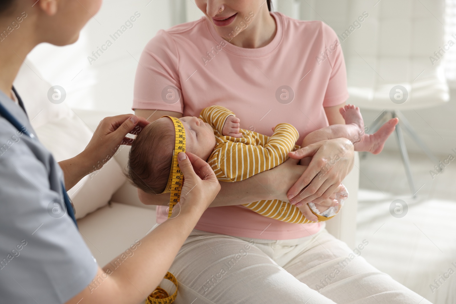 Mother and her cute little child having appointment with pediatrician in hospital. Doctor measuring baby's head, closeup Photo of Mother and her cute little child having appointment with pediatrician in hospital. Doctor measuring baby's head, closeup
