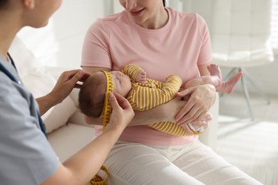 Photo of Mother and her cute little child having appointment with pediatrician in hospital. Doctor measuring baby's head, closeup