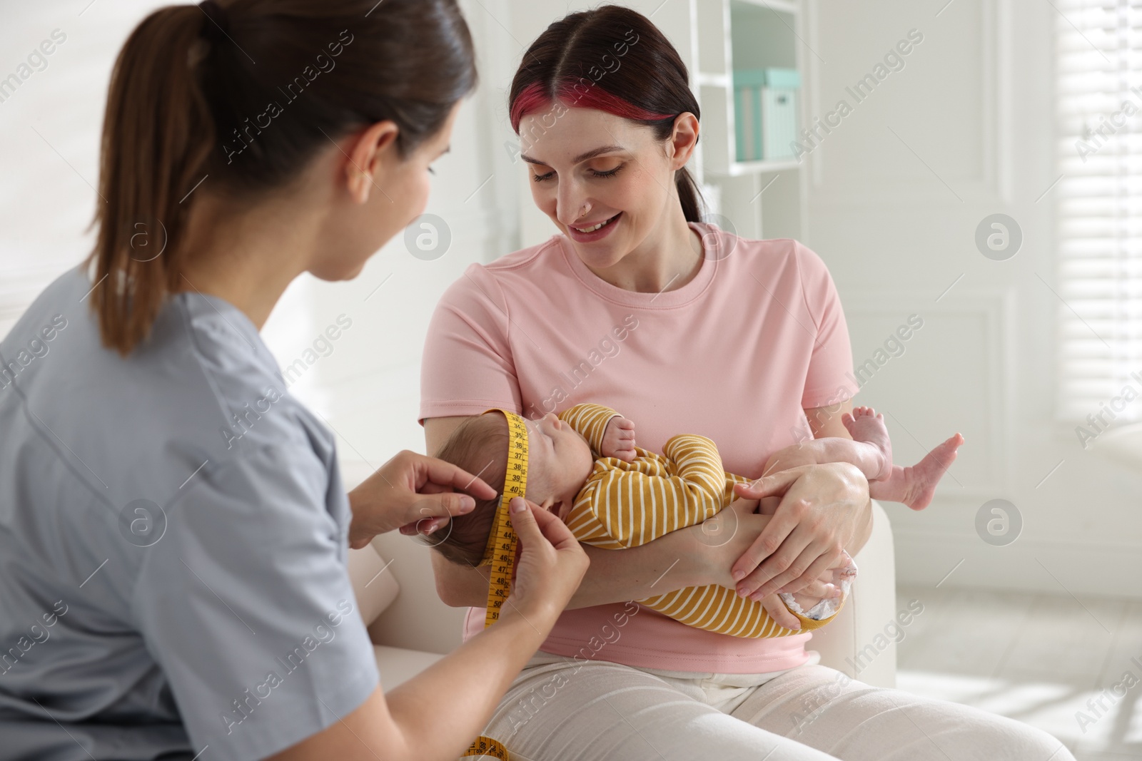 Mother and her cute little child having appointment with pediatrician in hospital. Doctor measuring baby's head Photo of Mother and her cute little child having appointment with pediatrician in hospital. Doctor measuring baby's head