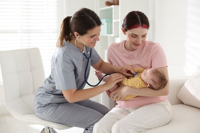 Photo of Mother and her cute little child having appointment with pediatrician in hospital. Doctor examining baby with stethoscope