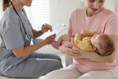 Photo of Mother and her cute baby having appointment with pediatrician in hospital, closeup