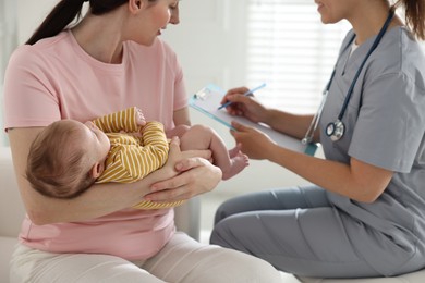 Photo of Mother and her cute baby having appointment with pediatrician in hospital, closeup